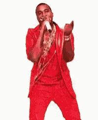 a man in a red suit is singing into a microphone while dancing .