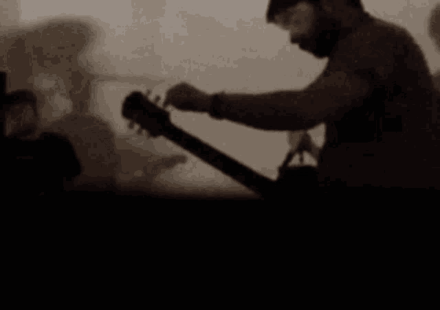a man with a beard is playing a guitar in a dark room