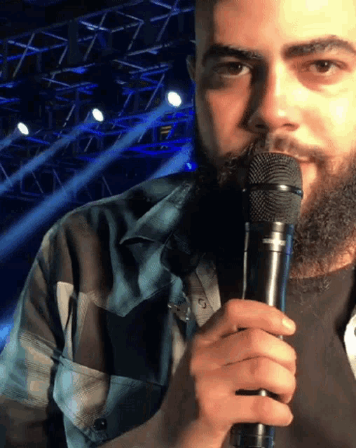 a man with a beard is holding a microphone with the letter c on the front