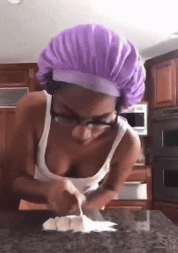 a woman wearing a purple chef hat and glasses is cooking