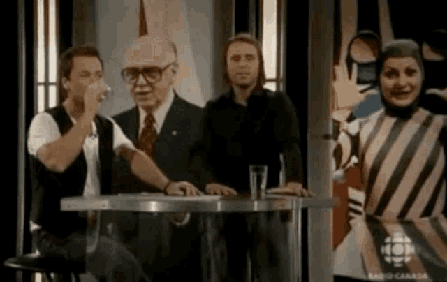 a group of people sitting at a table with a picture of a man and a woman behind them