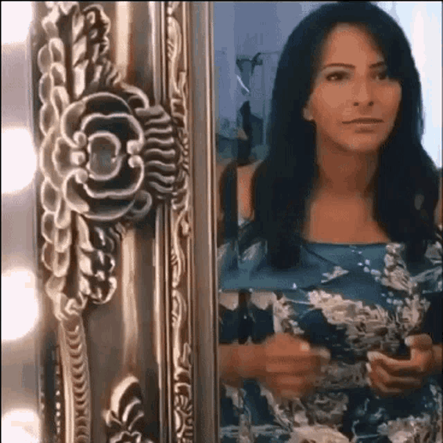 a woman is looking at her reflection in a mirror .
