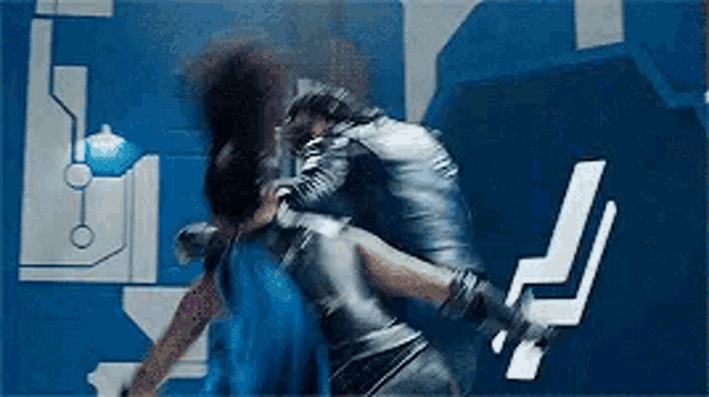 a man is holding a woman in his arms in front of a blue wall in a room .