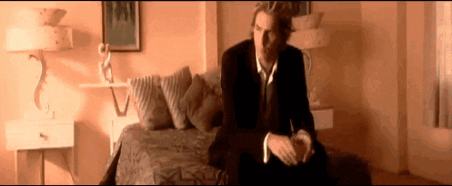 a man in a suit is sitting on a bed in a room .