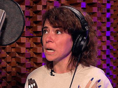 a woman wearing headphones is singing into a microphone and making a surprised face