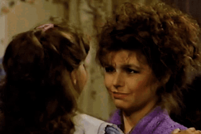 a woman with curly hair looks at another woman