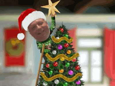 a man wearing a santa hat is putting a star on top of a decorated christmas tree