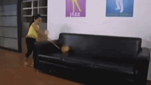a woman is standing next to a couch in a room with posters on the wall that say jazz .