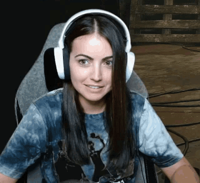 a woman wearing headphones and a tie dye shirt is sitting in a chair