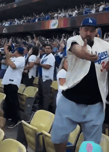 a man wearing a la dodgers jersey is dancing in the stands
