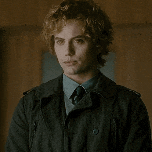 a man with curly hair wearing a black jacket and tie