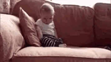 a baby is sitting on a couch with pillows .