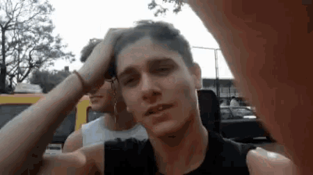 two young men are standing next to each other and one of them is holding his head .
