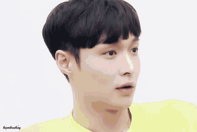 a close up of a young man wearing a yellow shirt making a funny face .