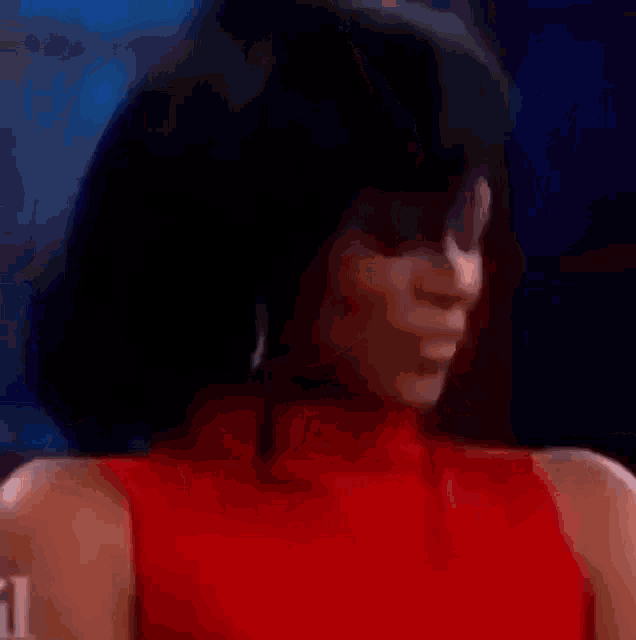 a woman in a red dress is smiling and making a funny face with her hand .