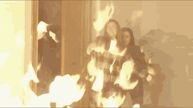 a group of people are standing in a room with fire coming out of the door