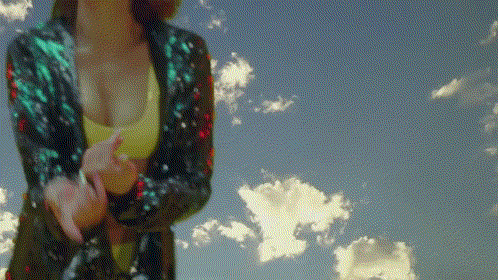 a woman is standing in front of a cloudy sky