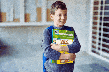 a young boy holding a book that says vuk on it