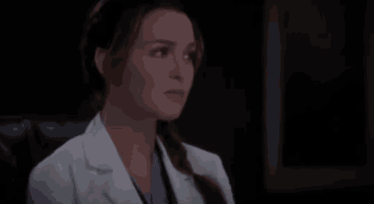 a close up of a woman in a lab coat looking at the camera .