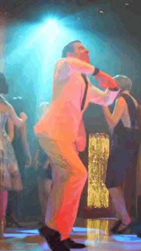 a man in a suit is dancing on a dance floor with other people