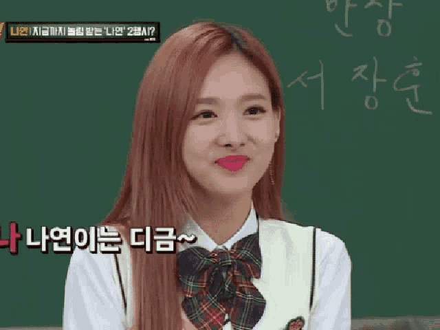 a girl with red hair is smiling in front of a blackboard with korean writing