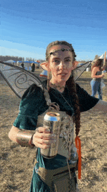 a woman in a fairy costume is holding a can of liquid gold beer