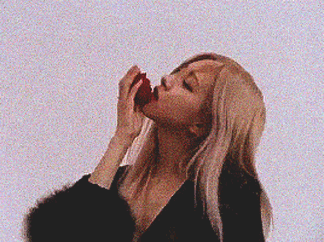 a woman is eating an apple with her mouth .