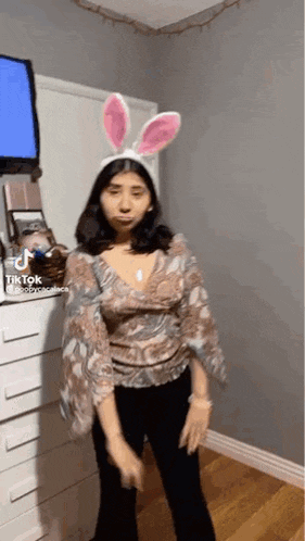 a woman wearing bunny ears is dancing in a bedroom .