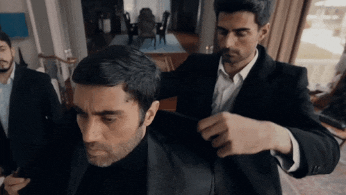 a man in a suit is being helped by another man in a suit