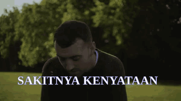 a man stands in a field with the words sakitnya kenyataan written below him