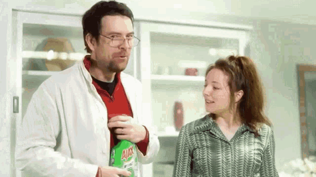 a man and a woman are standing next to a bottle of ajax