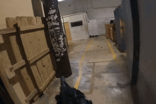 a person holding a gun in a hallway with a yellow line