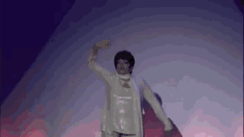 a woman in a white dress is dancing on a stage in a dark room .
