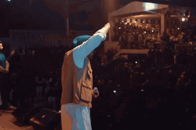 a man in a turban stands on a stage in front of a crowd and a sign that says paragon