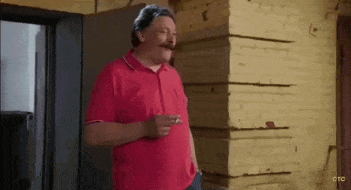 a man in a red shirt with a mustache is smoking a cigarette .