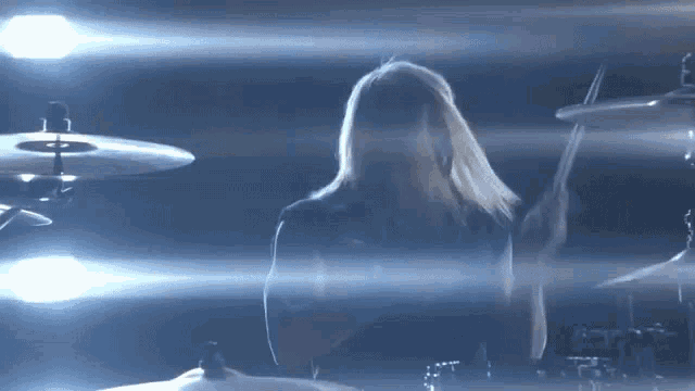 a woman playing drums in a dark room with a microphone