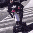 a person wearing a black adidas shirt is crossing a street
