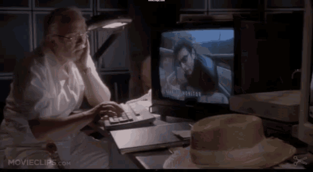 an older man sits in front of a computer monitor that says movieclips.com