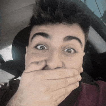 a man covering his mouth with his hand and making a surprised face