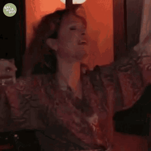 a woman in a robe is dancing in front of a sign that says oxi on it