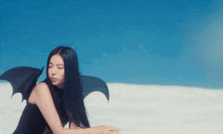 a woman in a black dress with bat wings is sitting in the snow