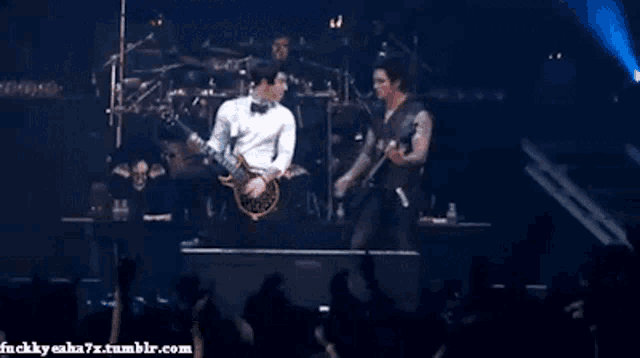 two men are playing guitars on a stage in front of a crowd ..