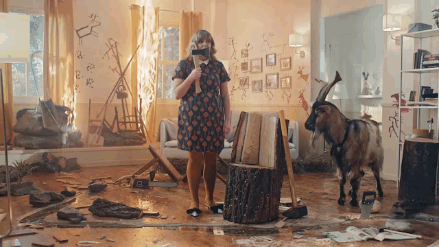 a woman in a dress is standing next to a goat in a room