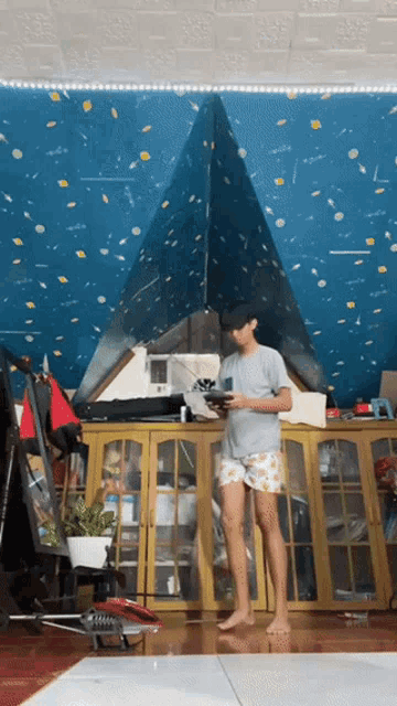 a man in shorts is standing in front of a blue wall with a triangle on it
