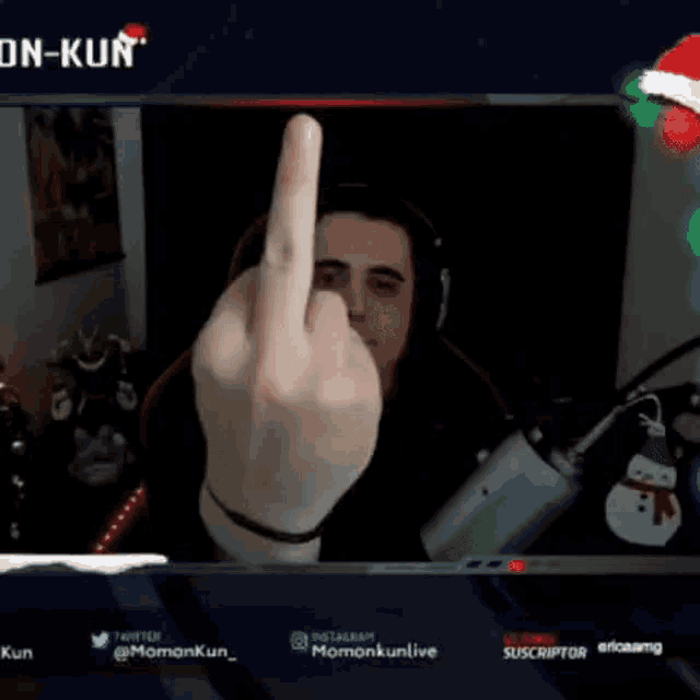 a man wearing headphones is sitting in front of a microphone with a santa hat on his head .
