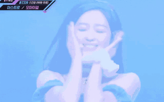 a woman is smiling with her hands on her face in front of a blue background with the number 2236 on it