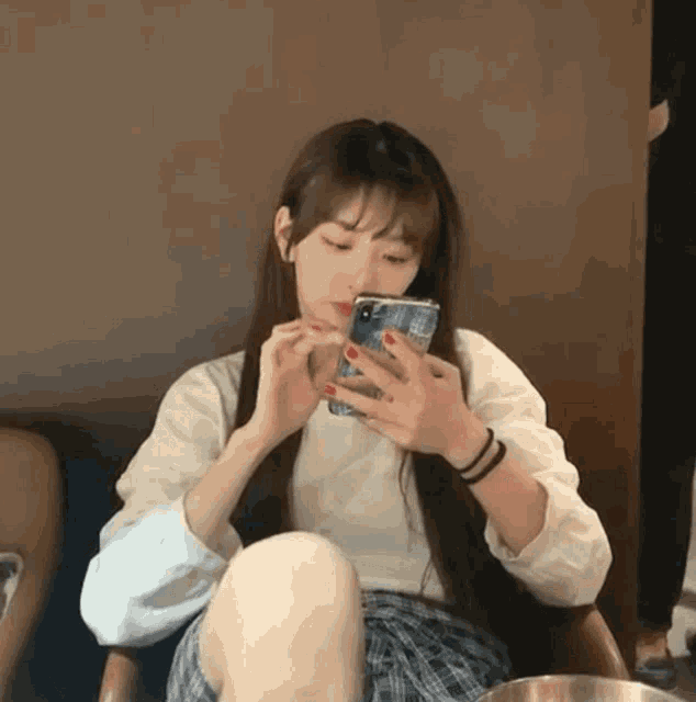 a woman sitting on a chair looking at her phone