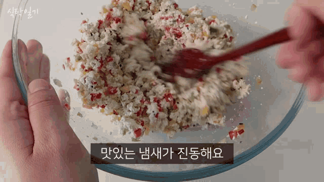a person is stirring a bowl of food with a wooden spoon