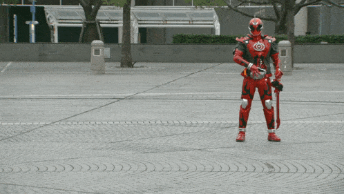 a man in a red superhero costume stands on a brick sidewalk