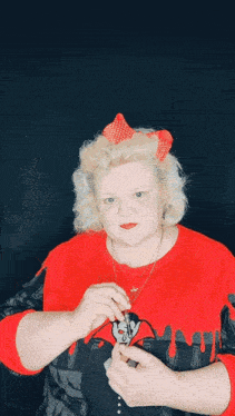a woman wearing a red shirt with a vampire on it is holding something